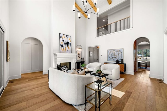 605 Claxton Ln, Milton, GA 30004 - living area featuring baseboards, arched walkways, light wood finished floors, a notable chandelier, and a fireplace