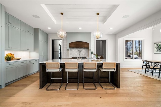 605 Claxton Ln, Milton, GA 30004 - kitchen featuring decorative backsplash, a tray ceiling, custom exhaust hood, and light wood-type flooring