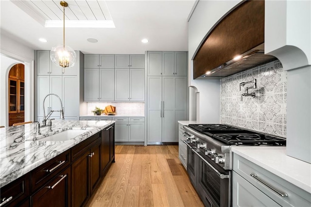 605 Claxton Ln, Milton, GA 30004 - kitchen featuring light wood-style flooring, arched walkways, a sink, custom range hood, and double oven range