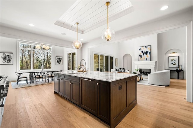 605 Claxton Ln, Milton, GA 30004 - kitchen featuring dark brown cabinetry, arched walkways, light wood-style floors, and a raised ceiling
