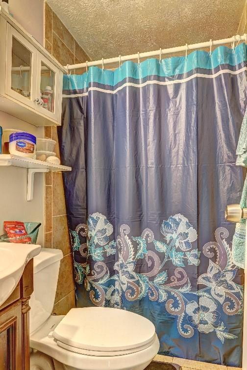 3576 Shrewsbury Ct, Snellville, GA 30039 - bathroom featuring toilet, vanity, curtained shower, and a textured ceiling