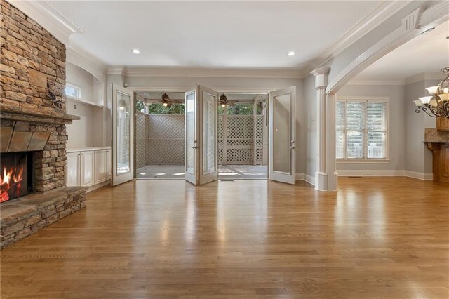 unfurnished living room with a fireplace, a notable chandelier, ornamental molding, and light hardwood / wood-style flooring