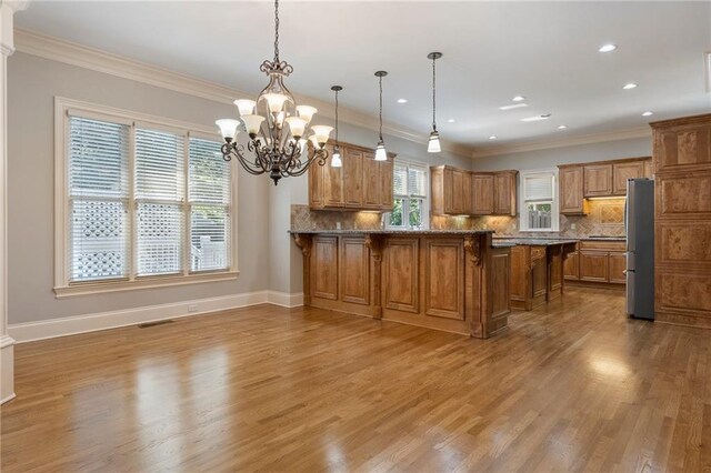 kitchen with crown molding, light hardwood / wood-style flooring, a kitchen breakfast bar, decorative light fixtures, and kitchen peninsula