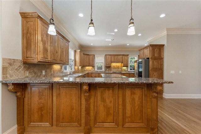 kitchen with kitchen peninsula, stainless steel fridge with ice dispenser, hanging light fixtures, and light hardwood / wood-style flooring