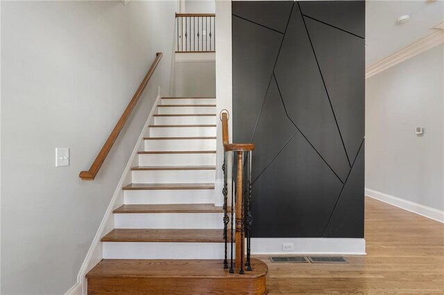 staircase featuring ornamental molding and wood-type flooring