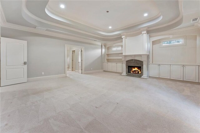 unfurnished living room with light colored carpet, crown molding, and a raised ceiling