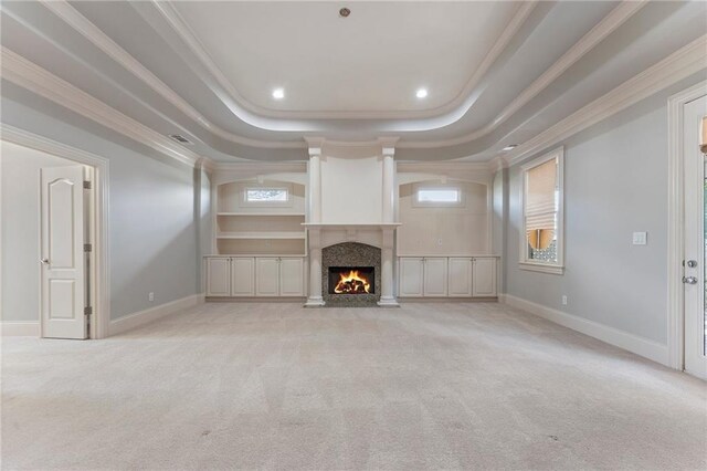 unfurnished living room featuring light colored carpet, a tray ceiling, crown molding, and a high end fireplace