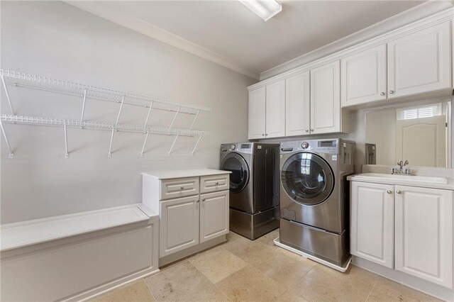 clothes washing area with ornamental molding, independent washer and dryer, sink, and cabinets