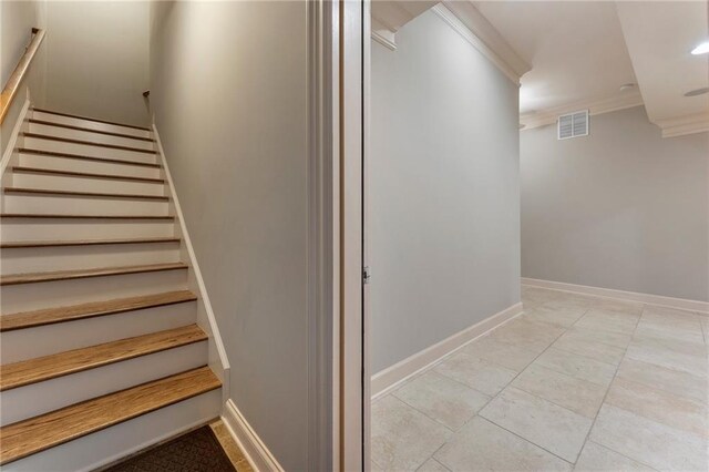 stairway featuring crown molding and tile patterned floors