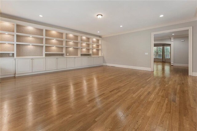 unfurnished living room featuring ornamental molding and wood-type flooring