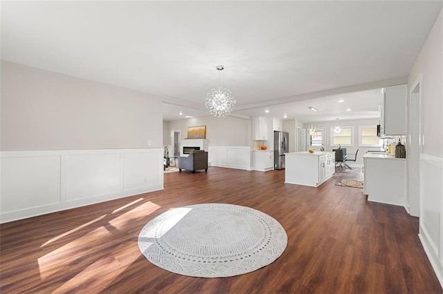living area featuring recessed lighting, a decorative wall, a chandelier, a wainscoted wall, and dark wood-style flooring