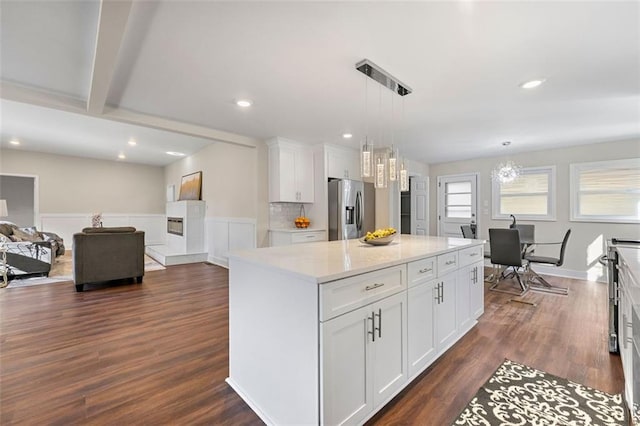 kitchen featuring pendant lighting, white cabinets, a center island, dark wood-style flooring, and stainless steel fridge