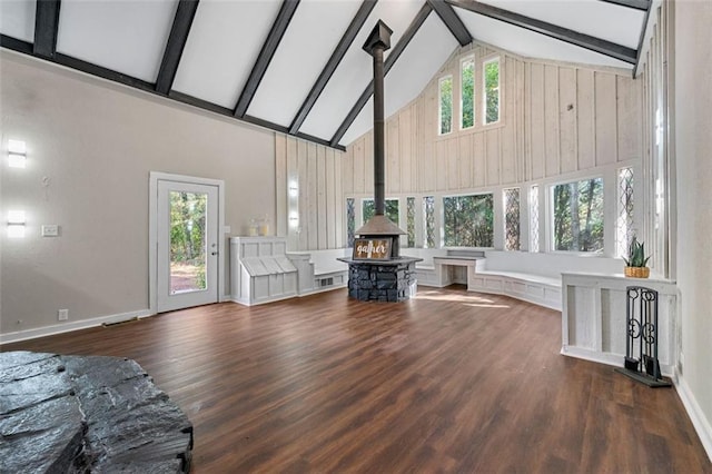 living room with a wood stove, beamed ceiling, wood finished floors, and high vaulted ceiling