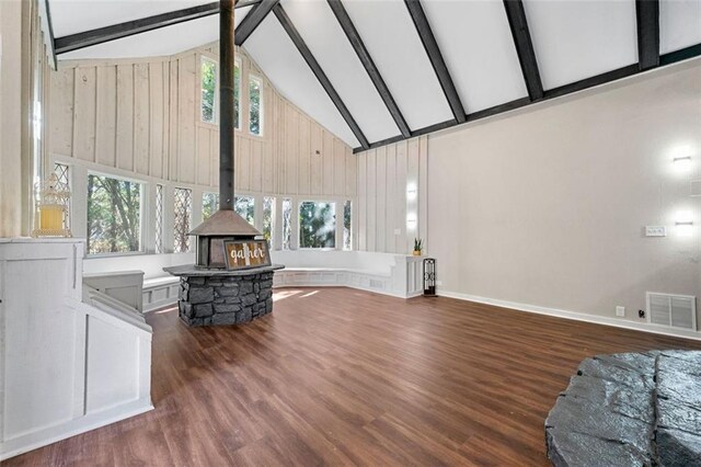living area featuring a wood stove, beam ceiling, high vaulted ceiling, a wealth of natural light, and visible vents