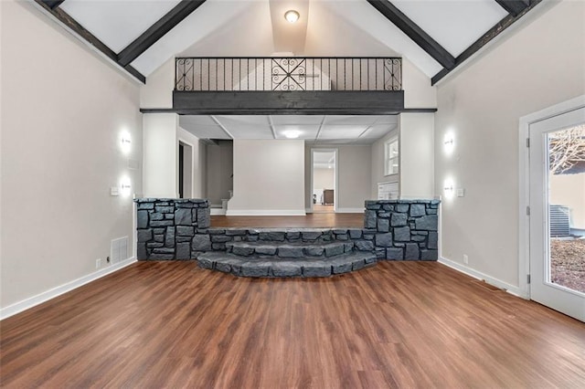 living area with wood finished floors, visible vents, high vaulted ceiling, and baseboards