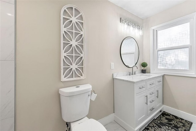 bathroom with toilet, marble finish floor, vanity, and baseboards