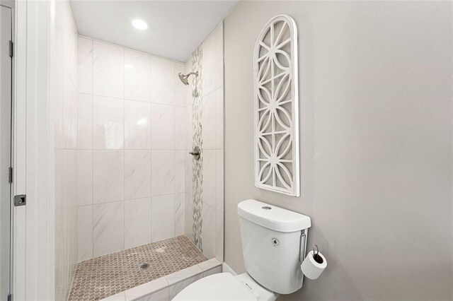 full bath featuring a tile shower, toilet, and recessed lighting
