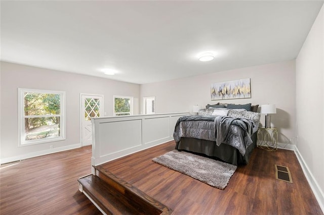 bedroom featuring visible vents, multiple windows, wood finished floors, and baseboards