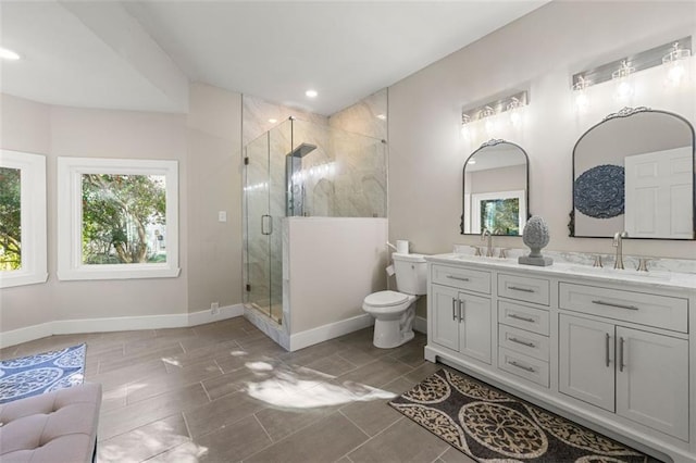 bathroom with double vanity, toilet, a stall shower, and a sink