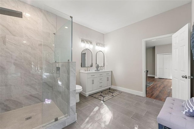 bathroom featuring toilet, walk in shower, vanity, and baseboards