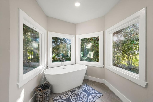bathroom with baseboards, a freestanding tub, and tile patterned flooring