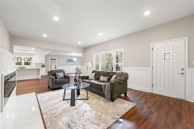 living area with wood finished floors, a decorative wall, a wainscoted wall, and recessed lighting