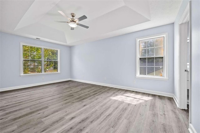 spare room featuring a raised ceiling, ceiling fan, and light hardwood / wood-style floors