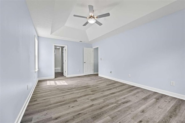 unfurnished bedroom featuring a raised ceiling, wood-type flooring, and ceiling fan