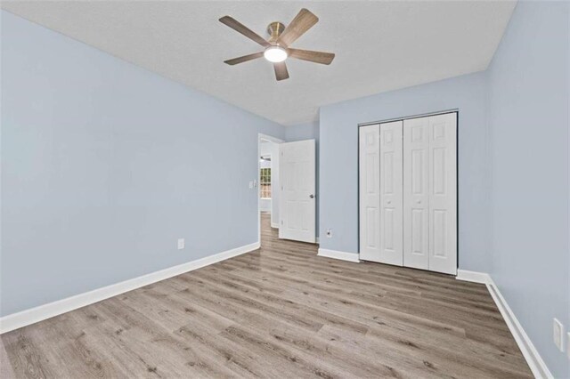 unfurnished bedroom featuring light hardwood / wood-style flooring, ceiling fan, and a closet