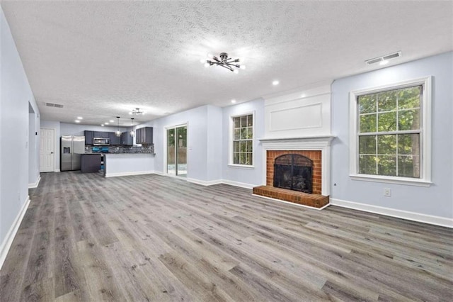 unfurnished living room with hardwood / wood-style flooring, a fireplace, and a textured ceiling