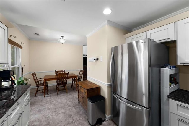 kitchen with ornamental molding, freestanding refrigerator, visible vents, and dark stone countertops