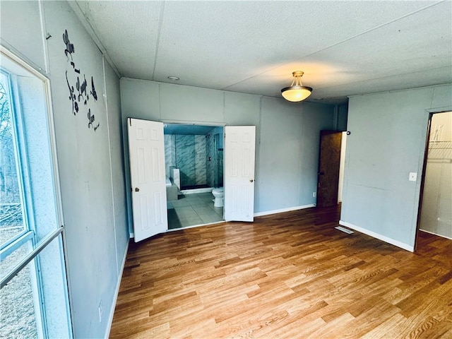 unfurnished bedroom featuring ensuite bathroom and light hardwood / wood-style floors