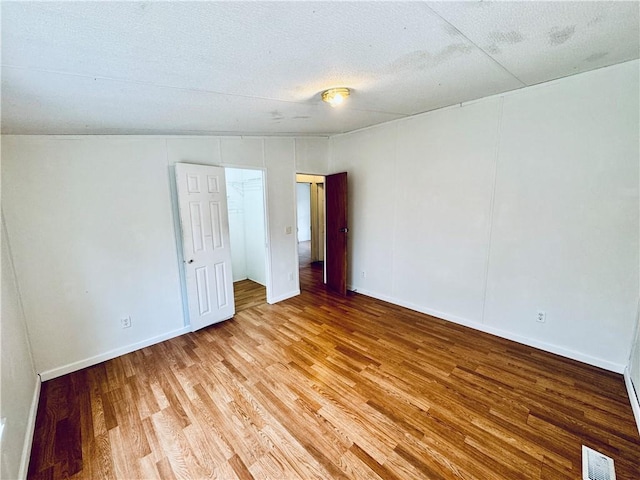 empty room with a textured ceiling and hardwood / wood-style flooring