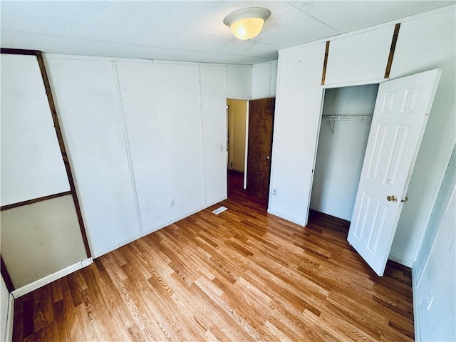 unfurnished bedroom with a closet and light hardwood / wood-style flooring