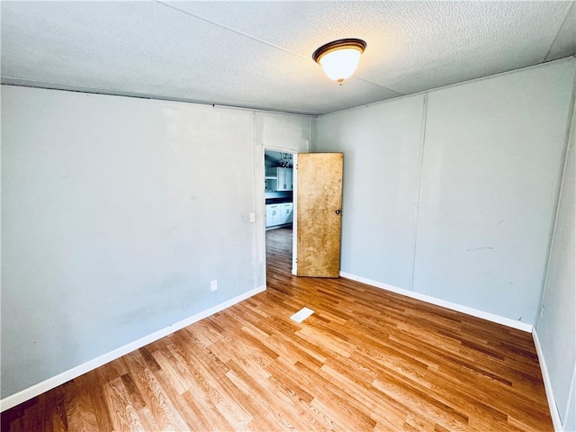 empty room featuring a textured ceiling and wood-type flooring