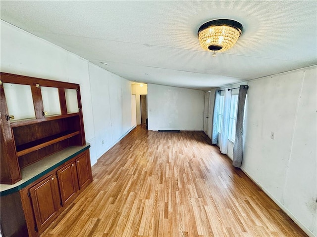unfurnished living room with light hardwood / wood-style floors and a textured ceiling