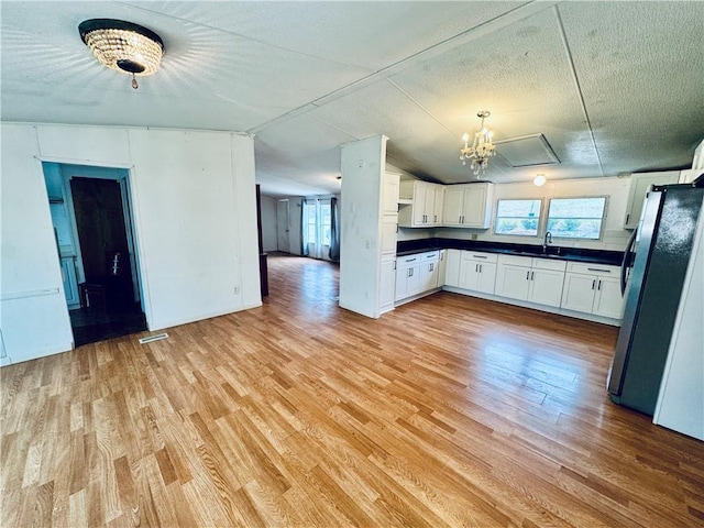 kitchen featuring white cabinets, stainless steel fridge, a wealth of natural light, and sink