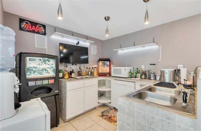 bar with light tile patterned flooring, hanging light fixtures, a sink, white appliances, and washer / dryer