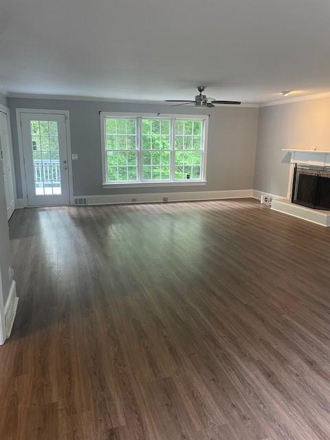 unfurnished living room featuring baseboards, ornamental molding, a ceiling fan, and wood finished floors