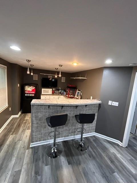 bar featuring dark wood-style flooring, baseboards, recessed lighting, bar area, and decorative light fixtures