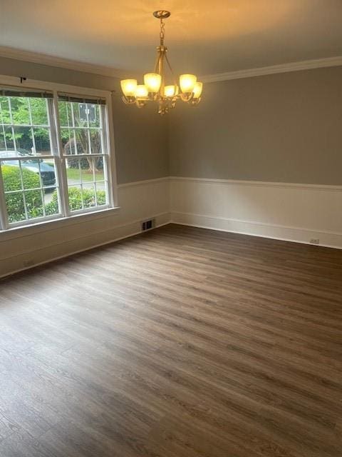 spare room with crown molding, visible vents, dark wood-style floors, and a chandelier