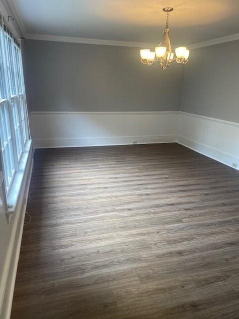 unfurnished room featuring crown molding, an inviting chandelier, dark wood-style floors, and a healthy amount of sunlight