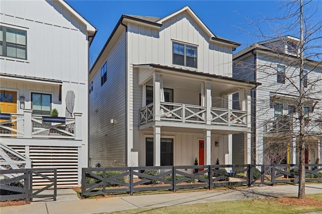 view of front of house with a fenced front yard, board and batten siding, and a balcony