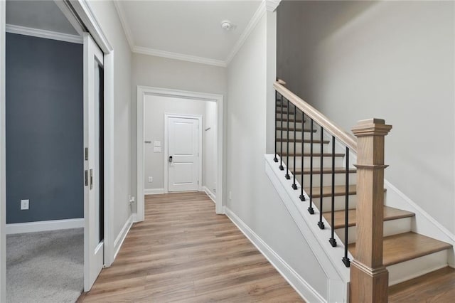 stairs with crown molding and hardwood / wood-style floors