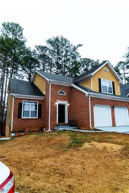 split level home with an attached garage, driveway, a front yard, and brick siding