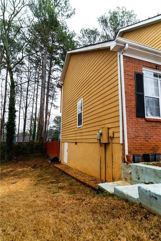 view of side of property with brick siding and a lawn