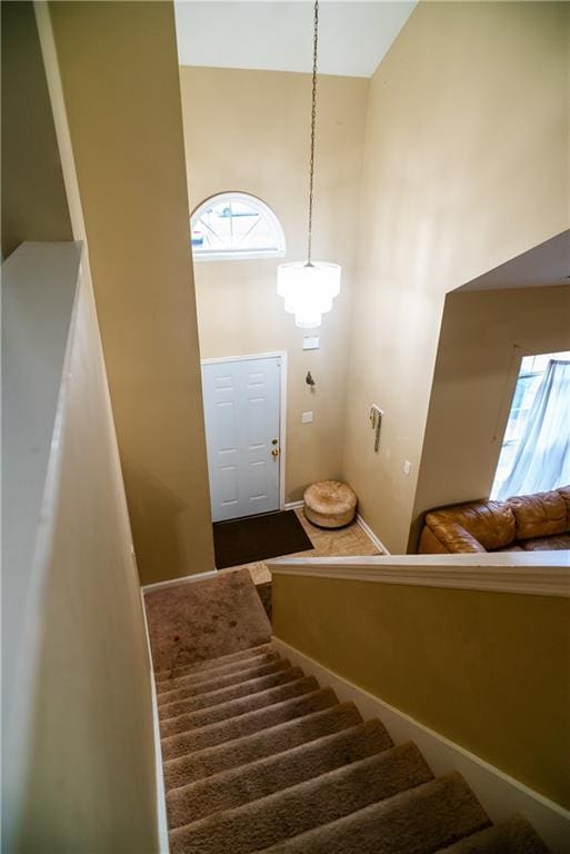 staircase featuring a towering ceiling and baseboards