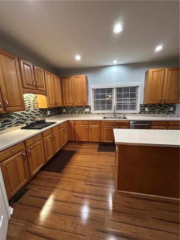 kitchen featuring dark wood-type flooring, gas cooktop, visible vents, and a sink