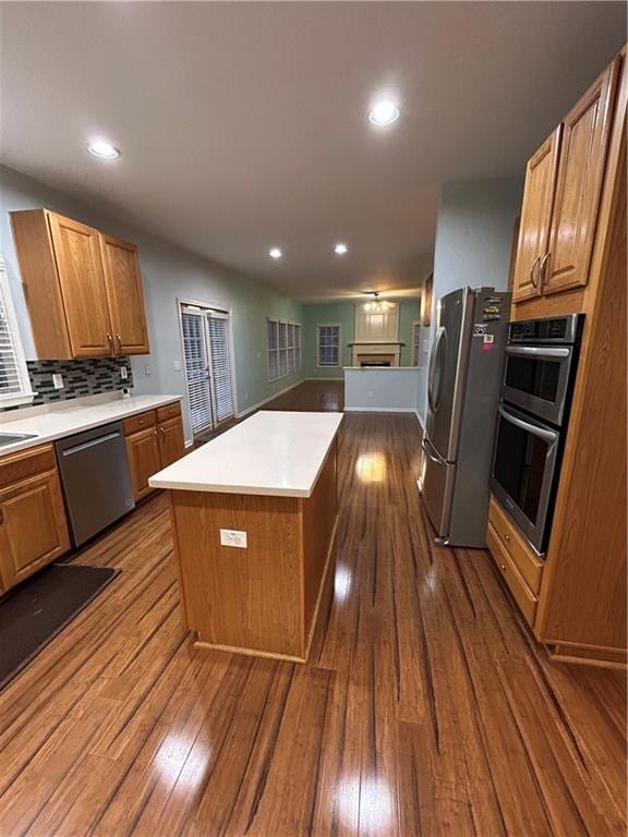 kitchen with backsplash, a center island, light countertops, dark wood-style floors, and stainless steel appliances