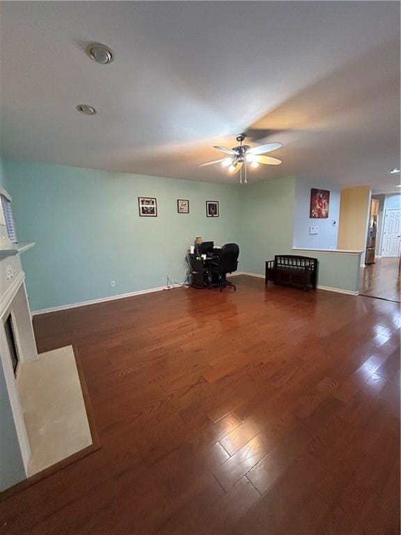 unfurnished room with dark wood-type flooring, a fireplace with flush hearth, baseboards, and ceiling fan